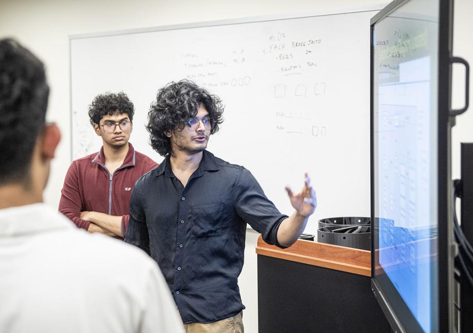 A student is gesturing at a video display