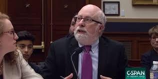 Image of Kenneth Stern, a balding white man with a trim white beard wearing glasses, a suit, and a purple tie.