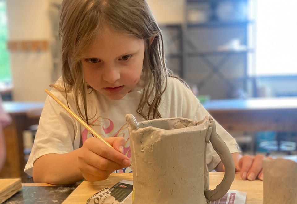 child painting pottery