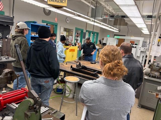 Professor teaching high school students in mechanical engineering lab