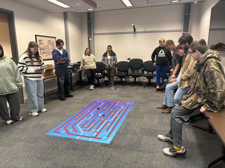 High school students gathered to race robots on mat on the floor