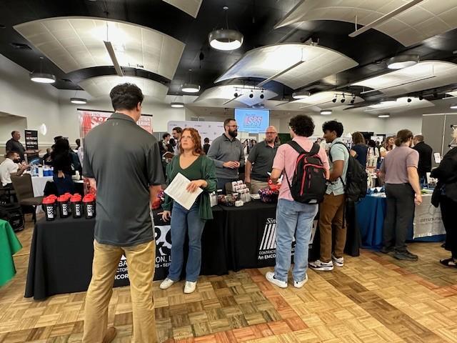 Students speaking with prospective future employers at career fair booth