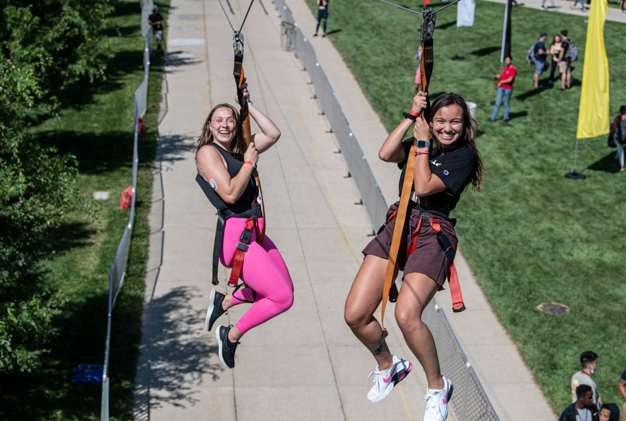 Two females smiling riding on a zipline