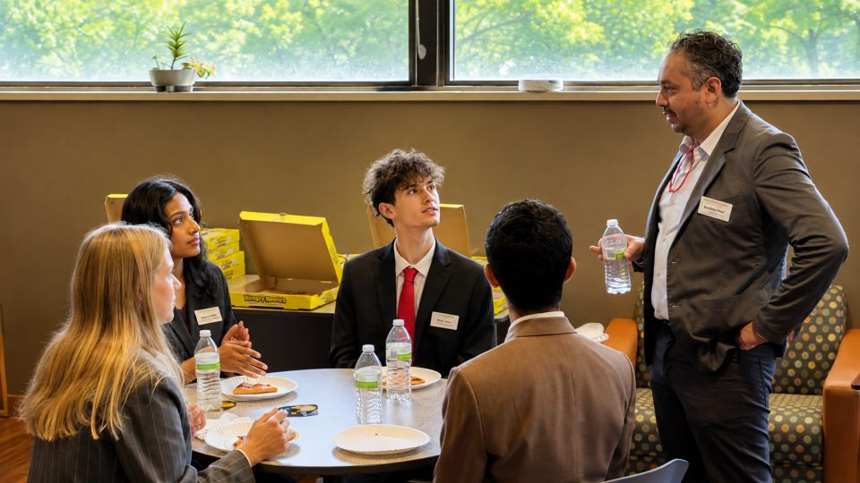 Photo of professor speaking with students.