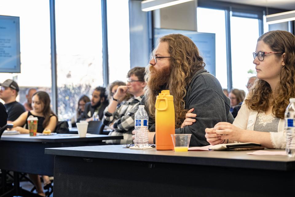 Students sitting at tables listening to a presenter.