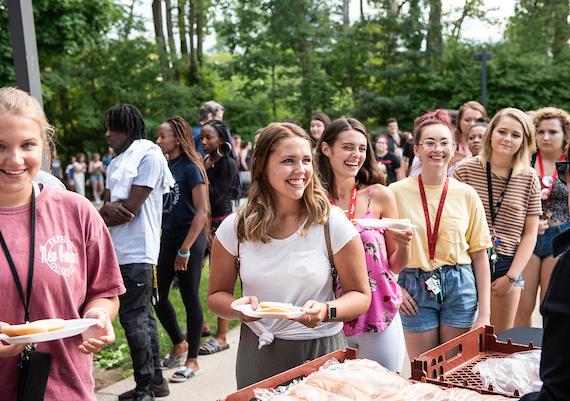 Smiling students standing in line for a meal at campus kickoff