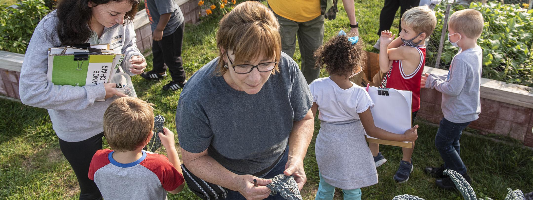 A group of faculty, students, and children at the Extension Garden