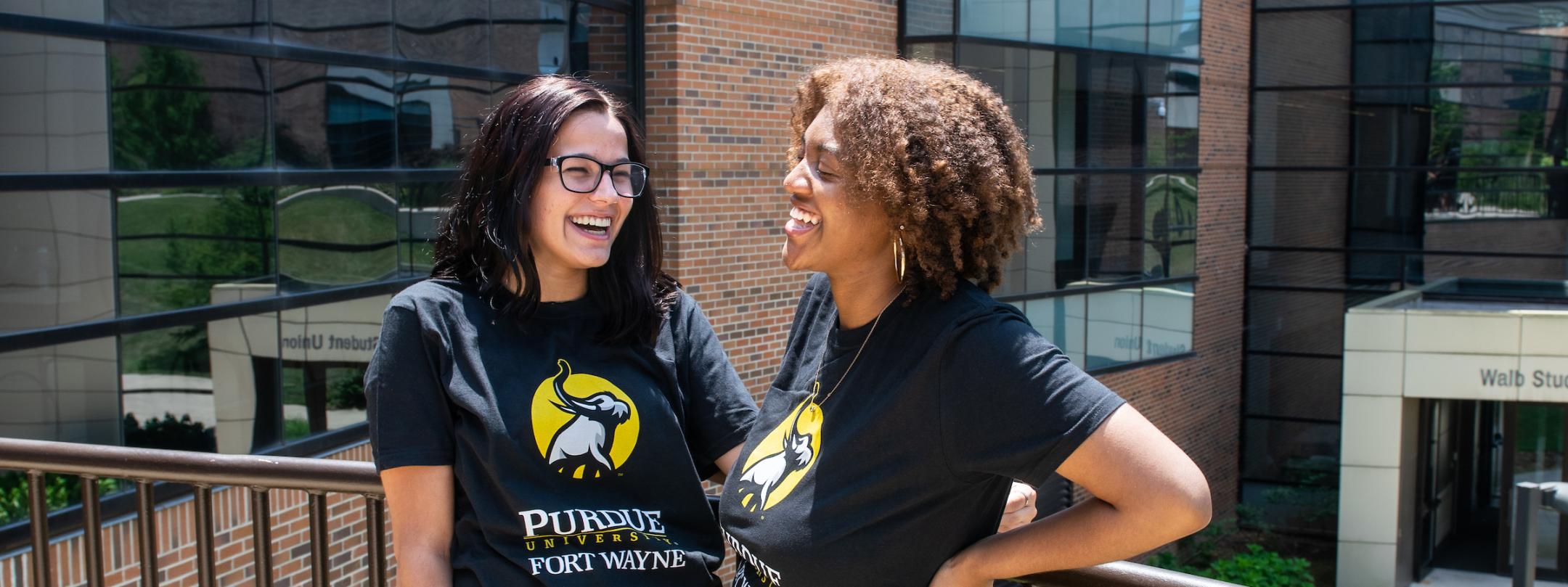 Two transfer students stand outside wearing PFW Transfer shirts.