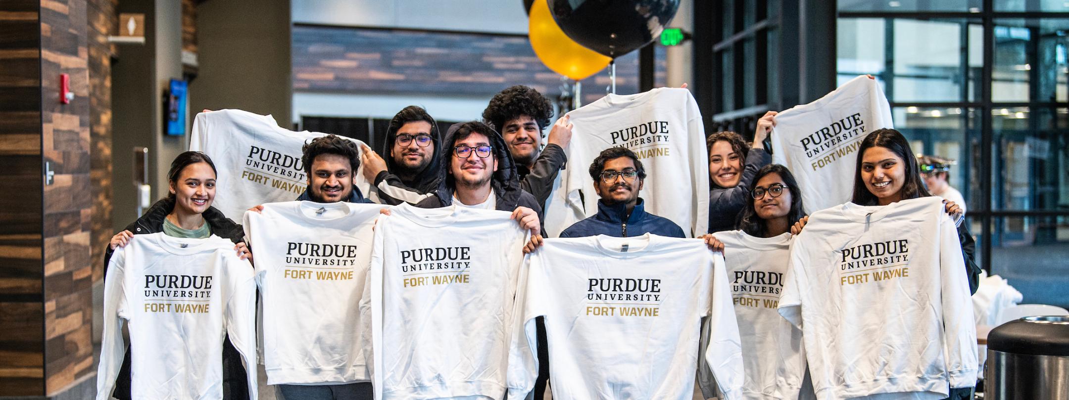 Students hold up PFW sweatshirts.