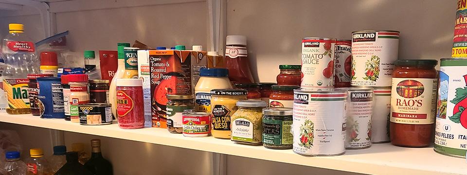 Close up of canned goods on a white pantry shelf