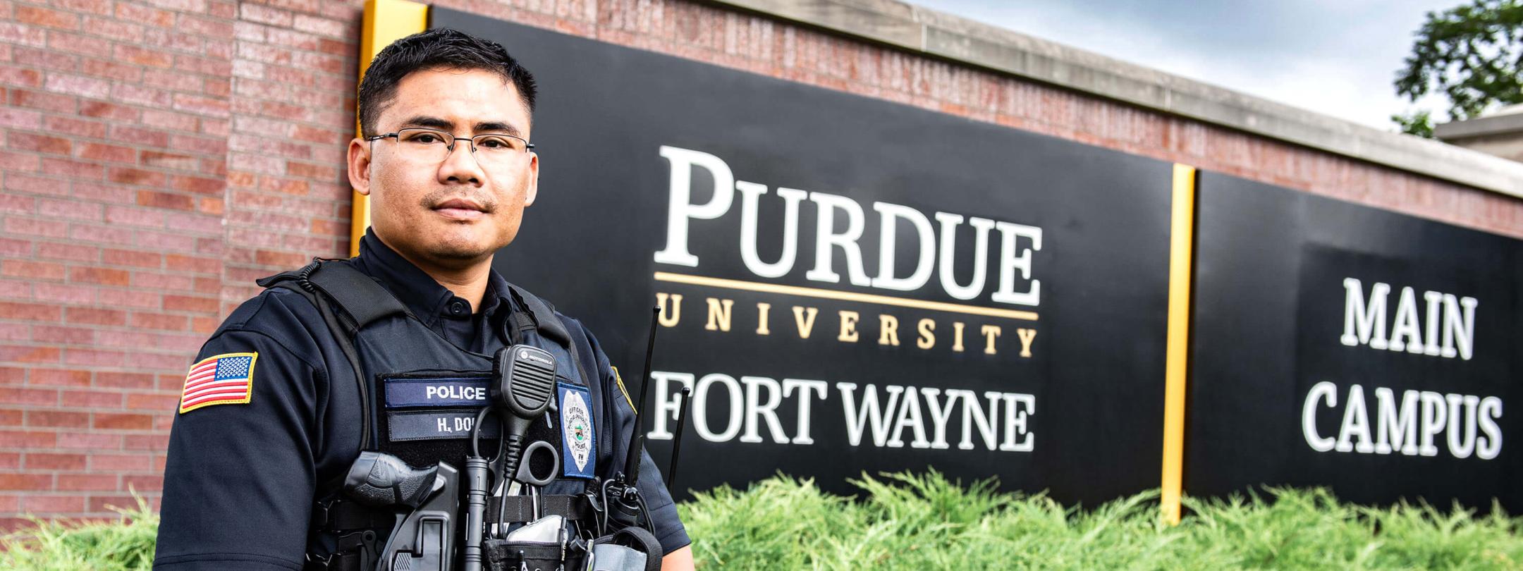 PFW police officer Htoo Doh is standing in front of the Purdue Fort Wayne main campus sign