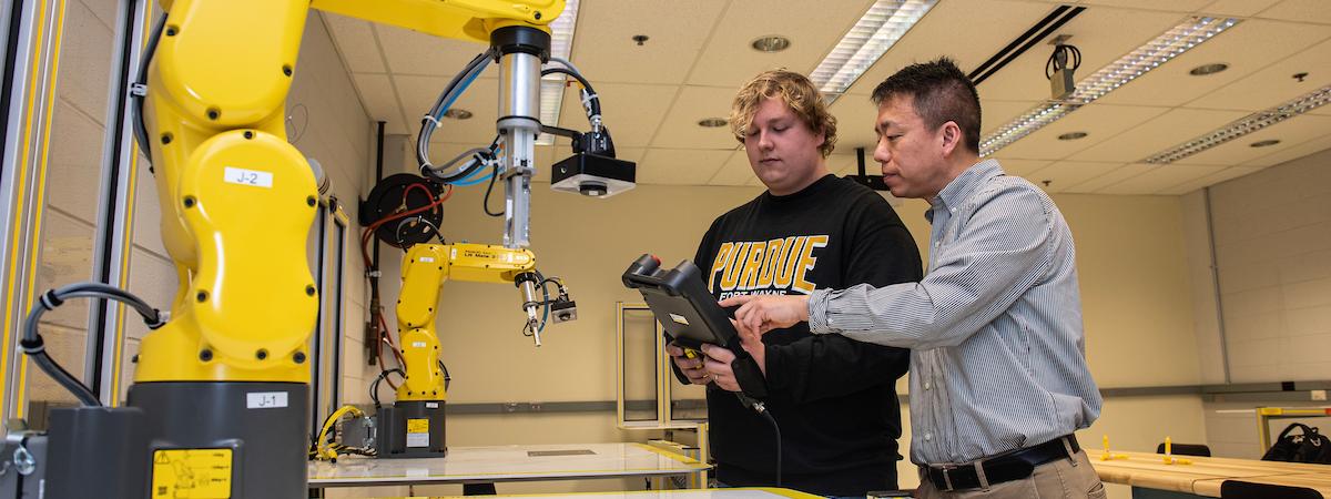 Student works in an engineering lab with a robotic arm.