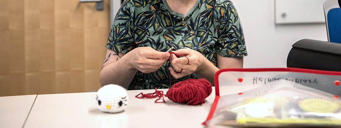 A person holds a crochet hook and yarn.
