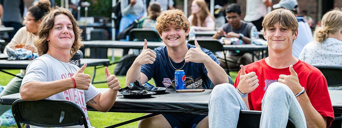 Three students are enjoying a campus kickoff event.