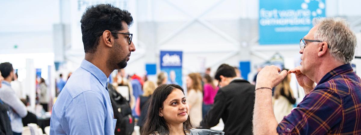 Two students interact with someone at a career expo.