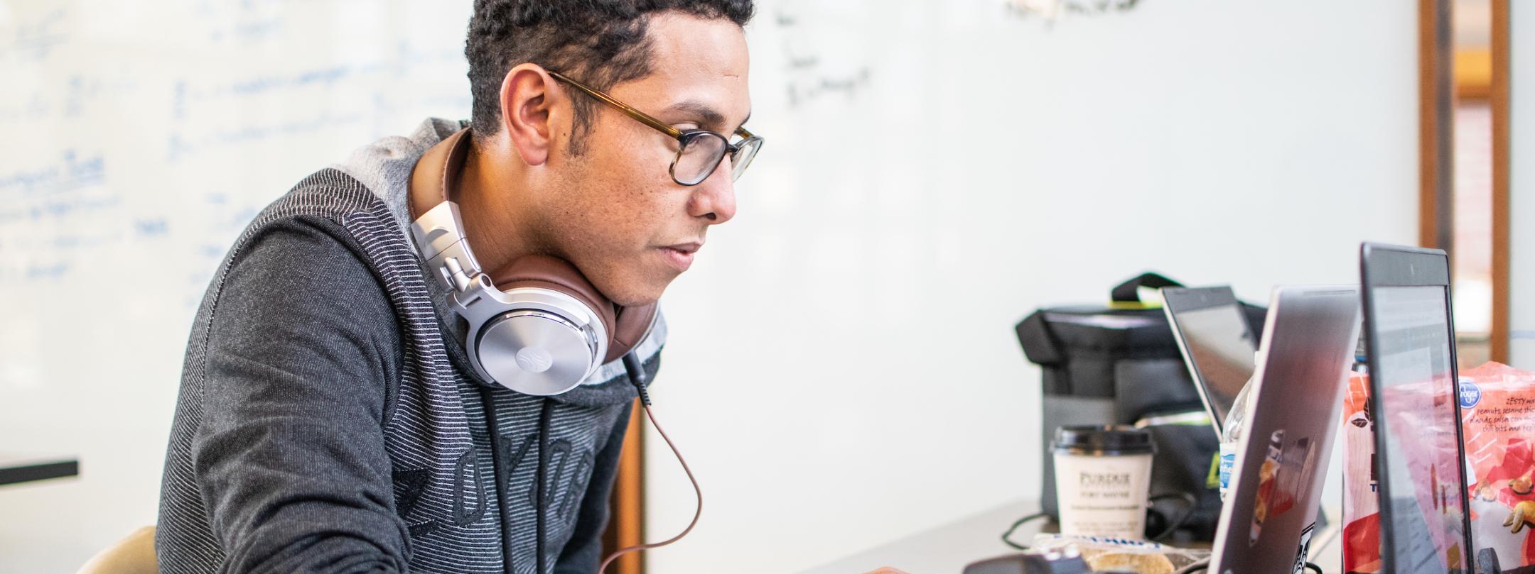 Student with camera equipment working on a laptop