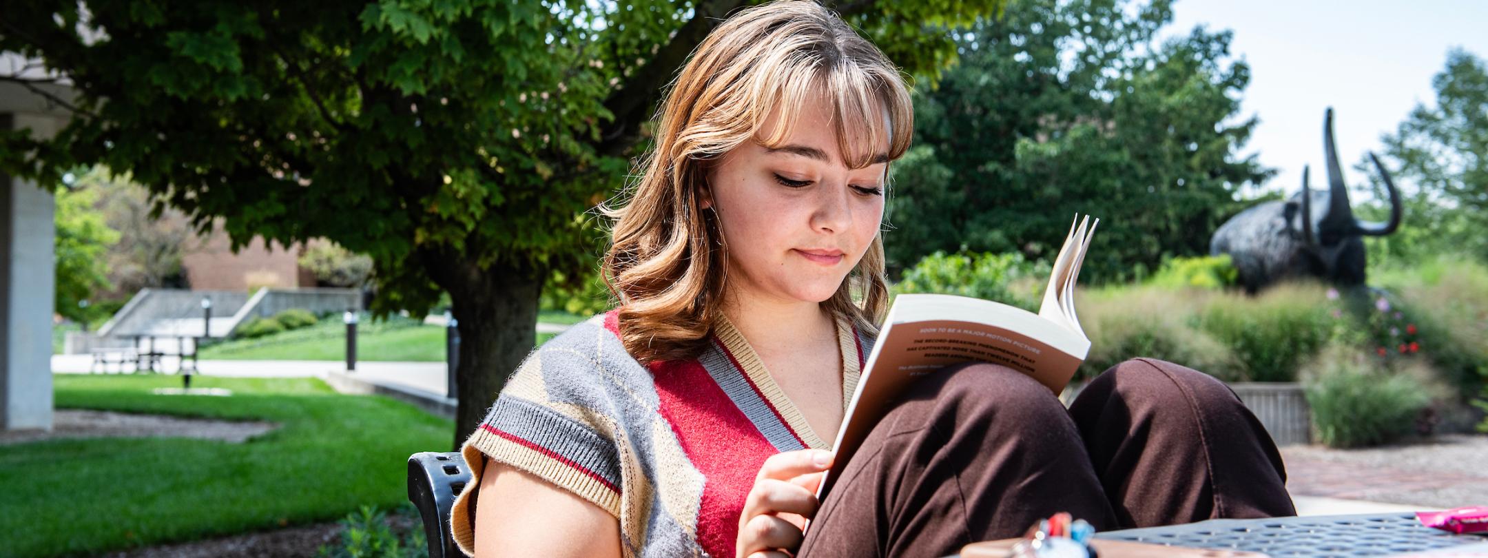 Student reading a book outside.