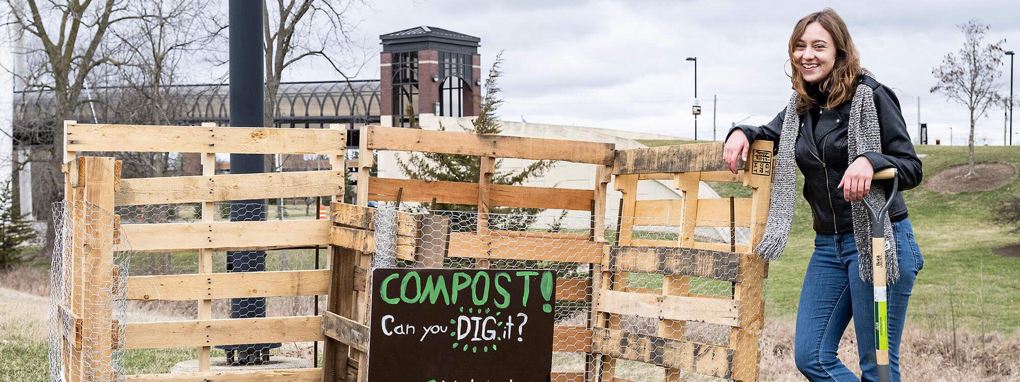Emma Coville is standing next to compost bin