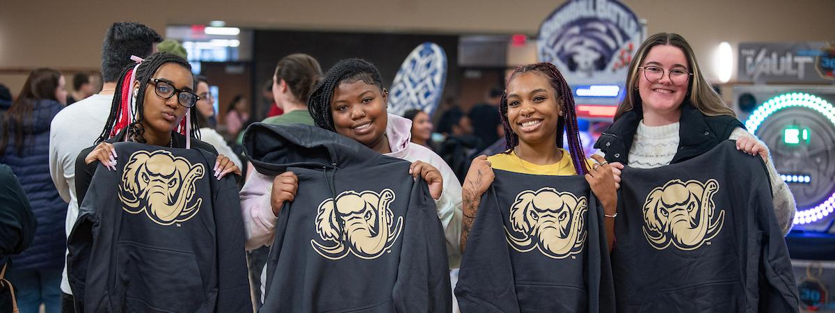 Students hold up Mastodon-printed sweatshirts.