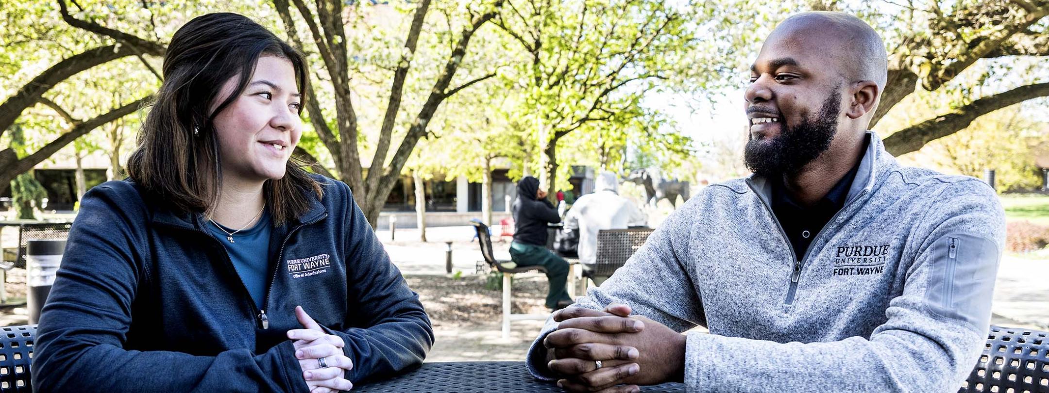 Madeline Minobe and DeShawn Woods are sitting at a table