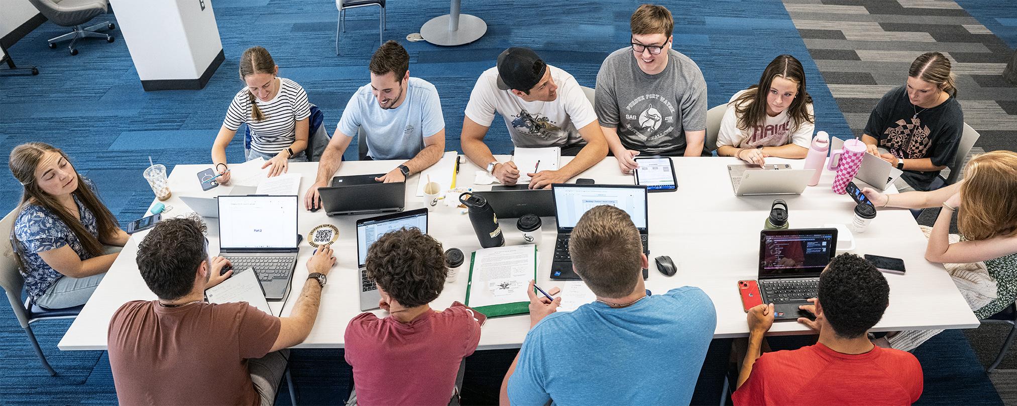 Students studying in a large group at a table in Helmke Library.