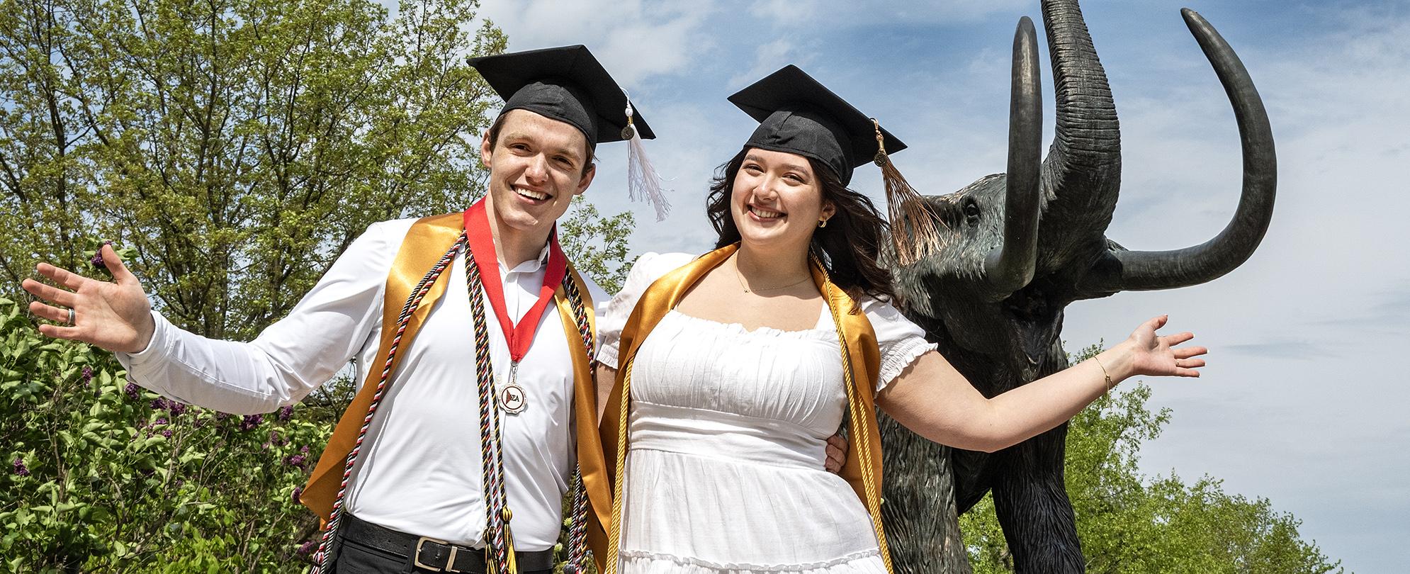 Graduating students pose in front of the Mastodon statue.
