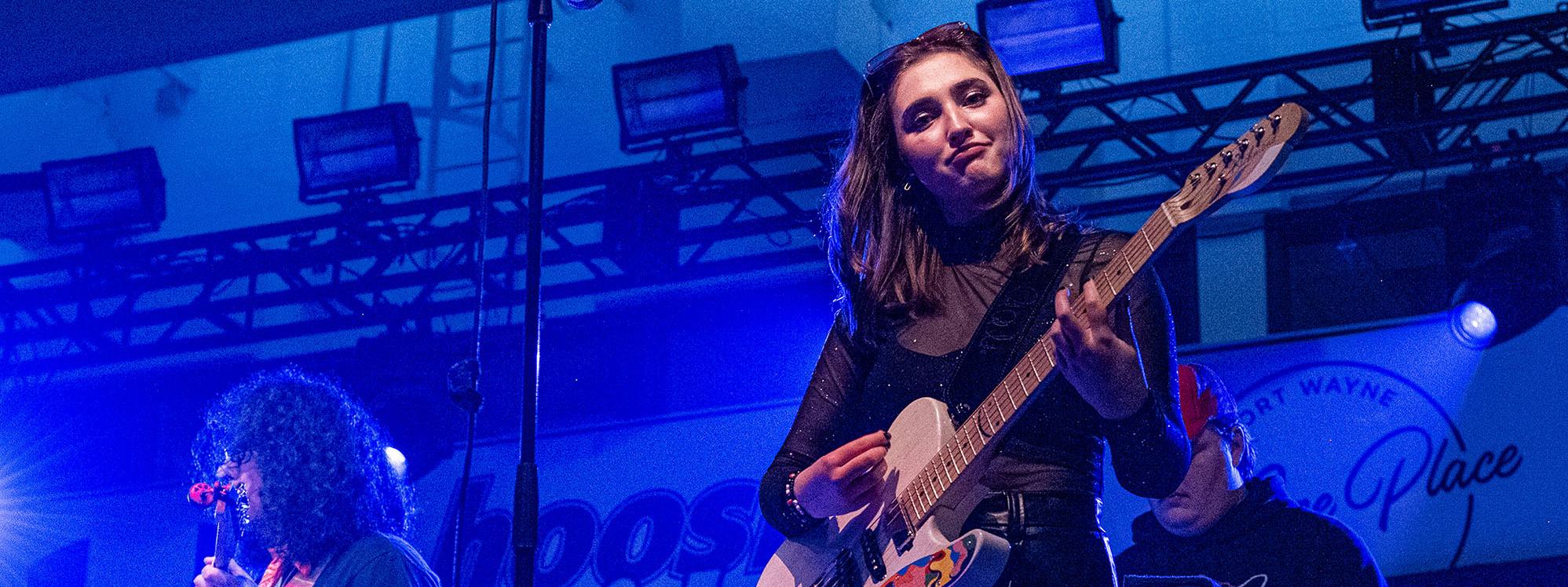 Hailee Richmond is playing guitar while performing with a band