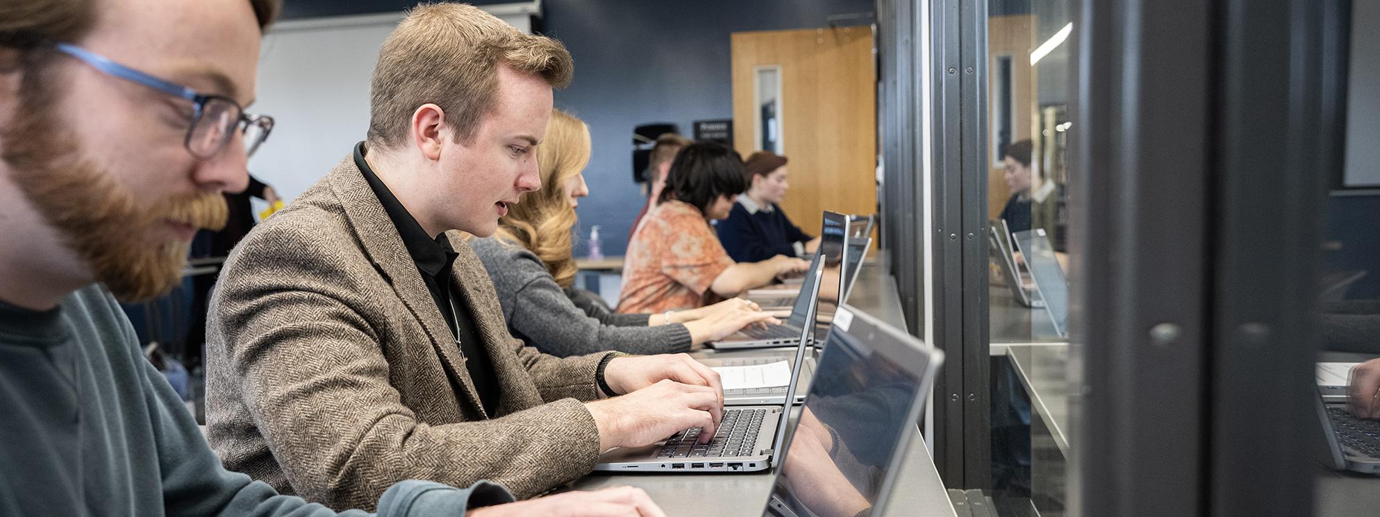 Students working on laptops in a classroom.