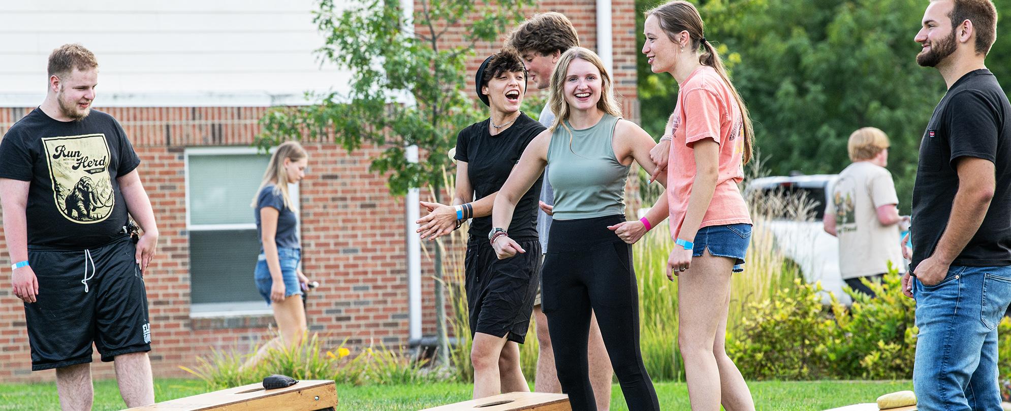 Students playing corn hole outside on campus.