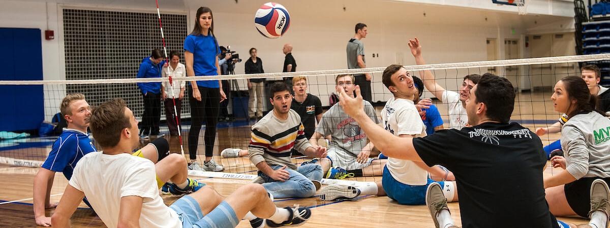 Two teams are playing volleyball while sitting down