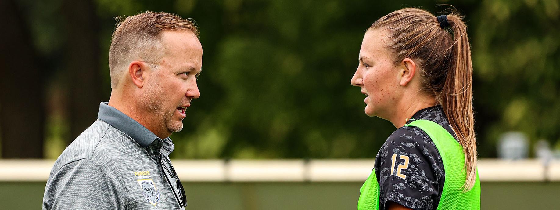 A coach is conferring with a soccer player