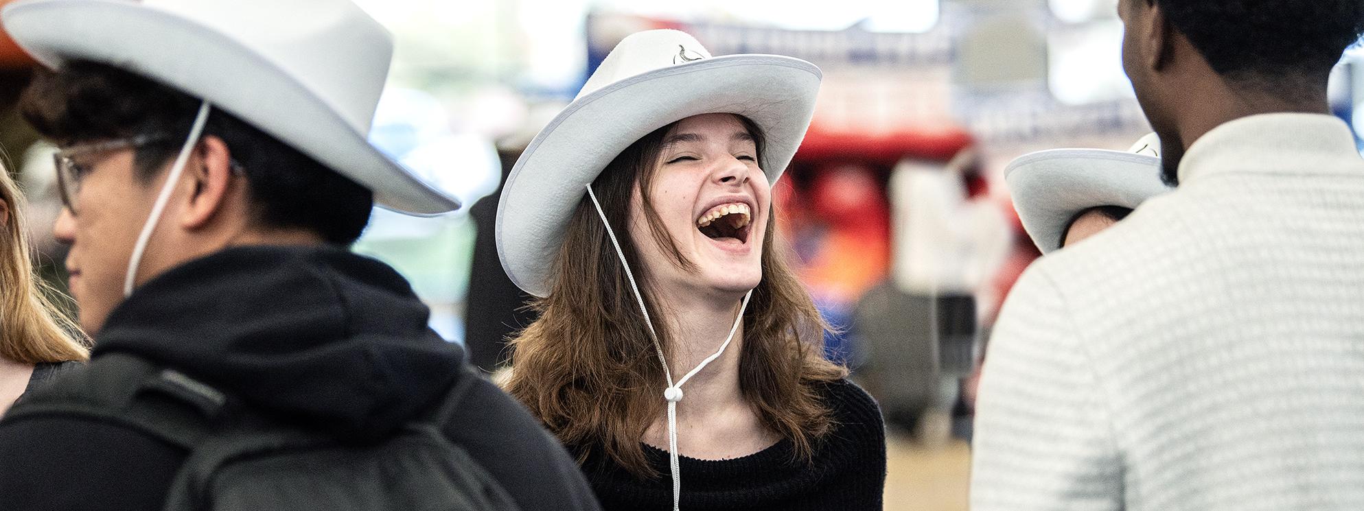 Student laughing with a cowboy hat.