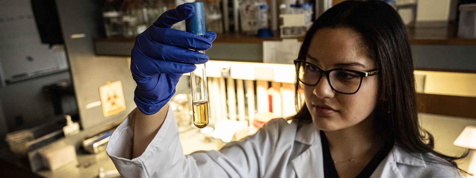 Student in lab holding vial.