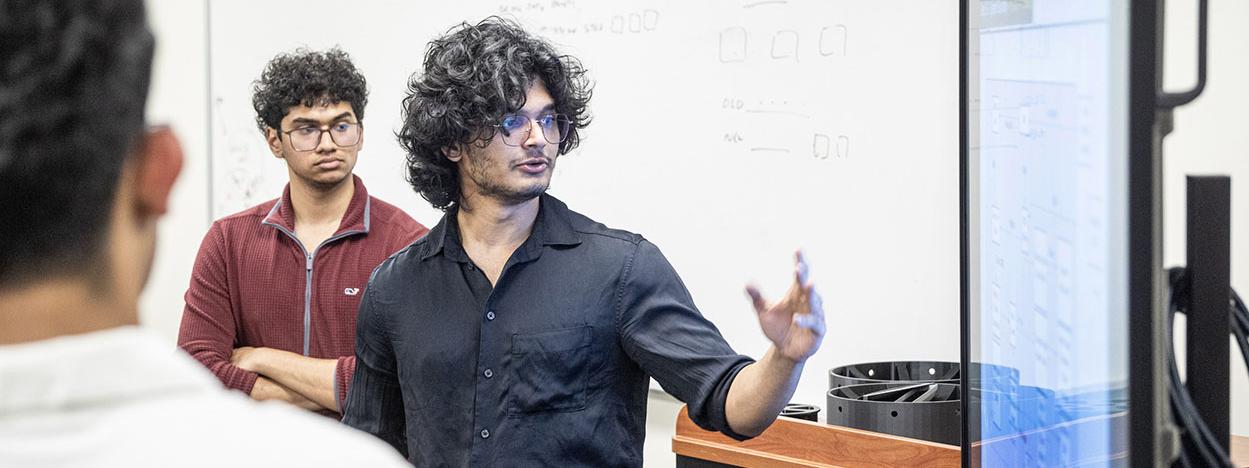 A student is gesturing at a video display