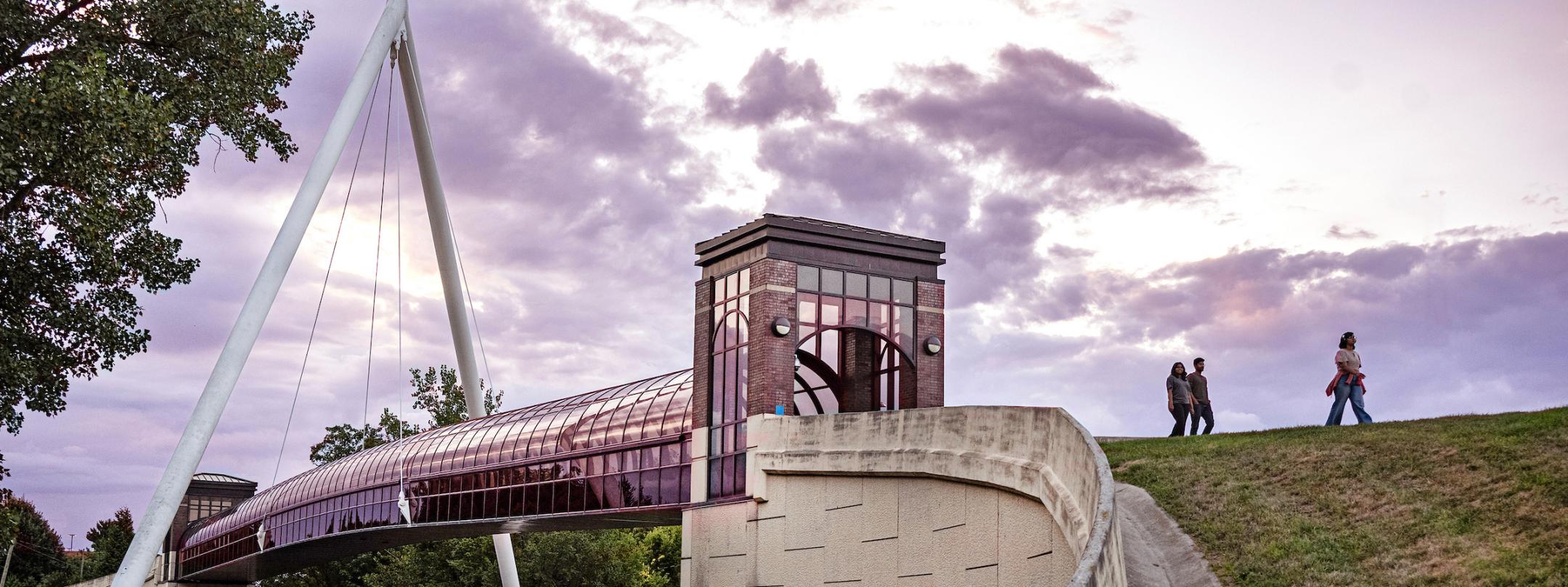 Students are walking across Wolf Bridge at sunset