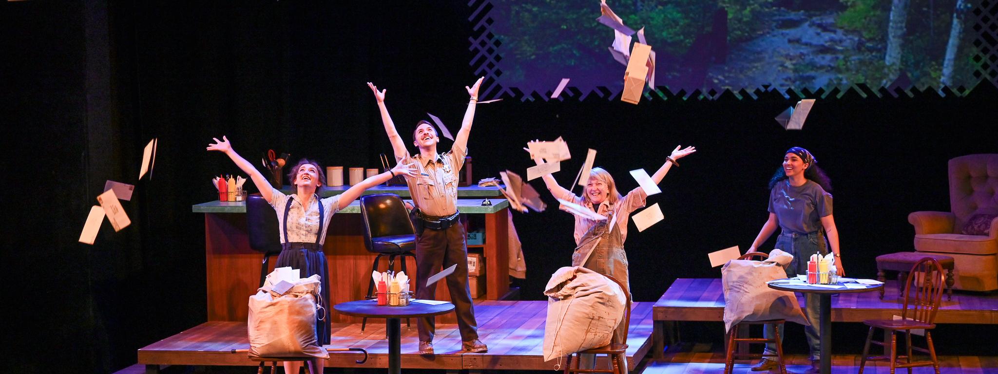 Actors performing in The Spitfire Grill, they are throwing letters into the air in a diner setting