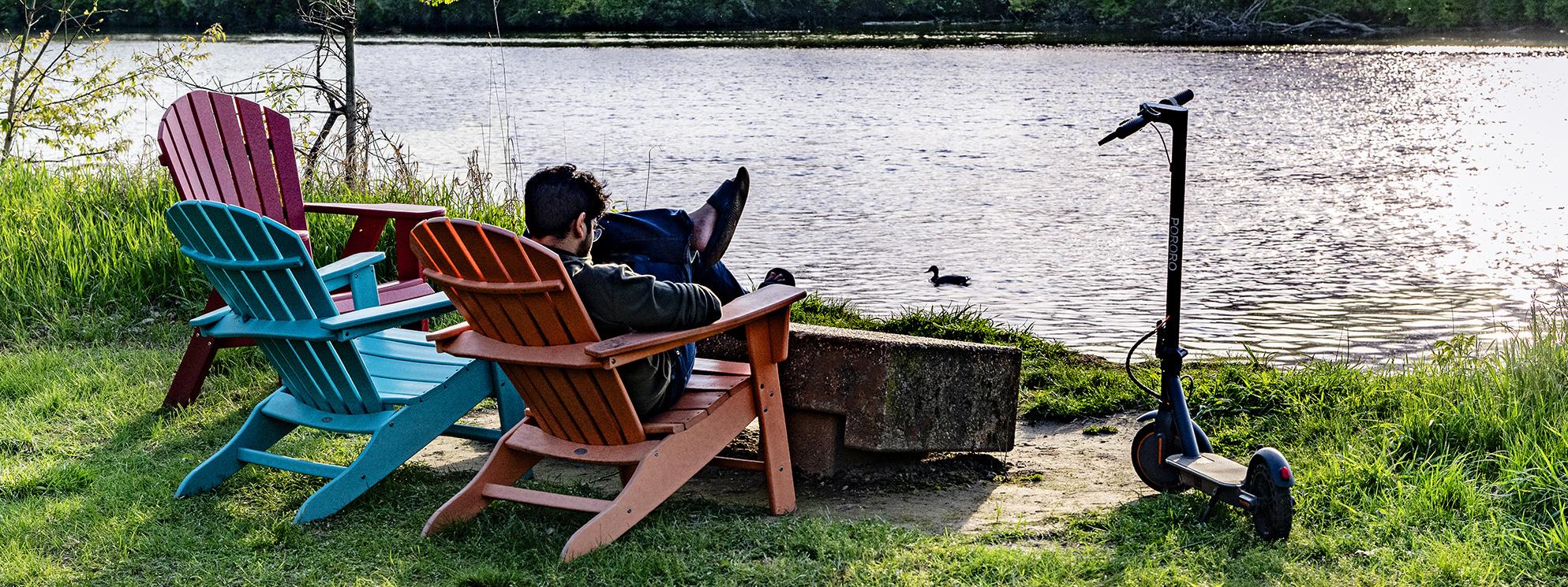 A student relaxes by the river on a summer evening