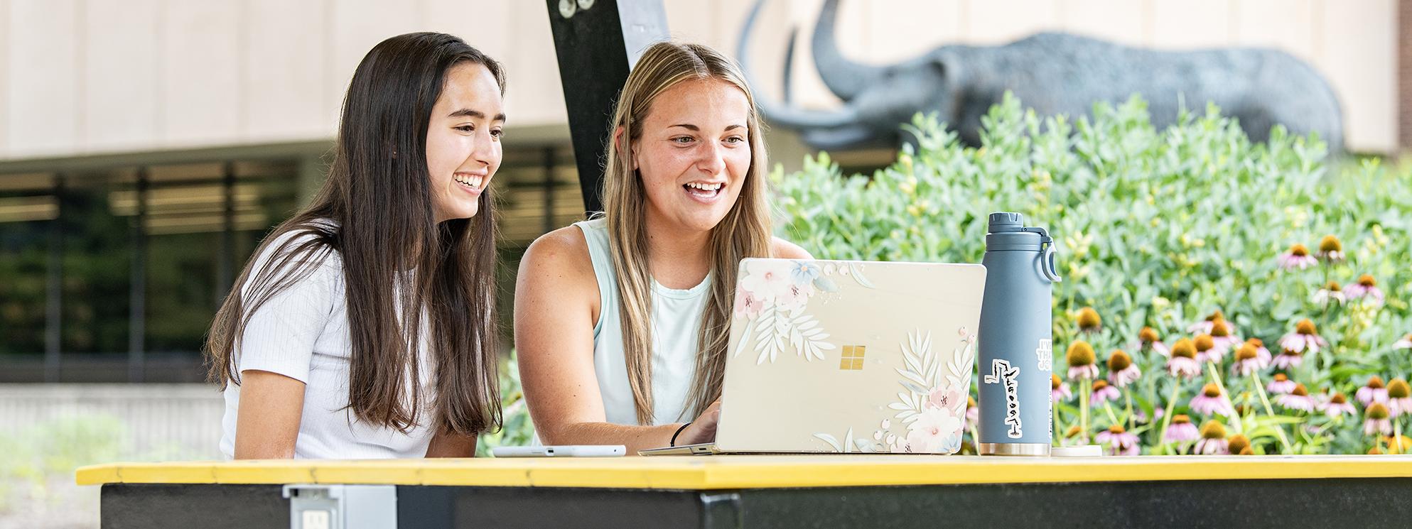 Two students relax on campus in the summer