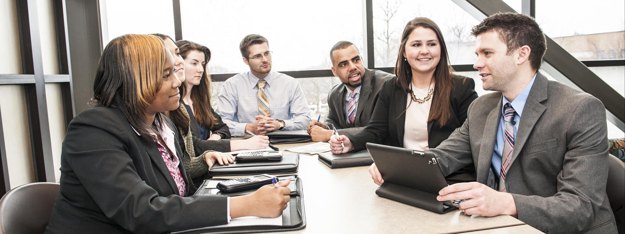 A diverse group at a table in business attire