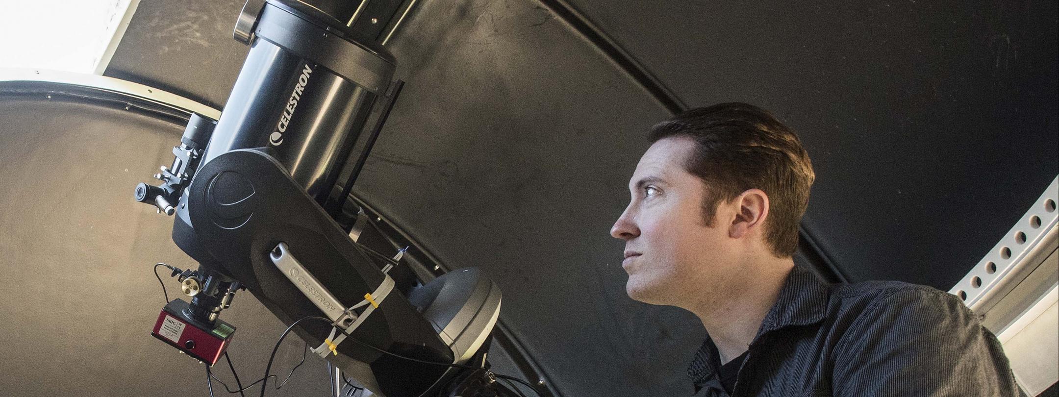 Physics student using a telescope in the observatory lab.