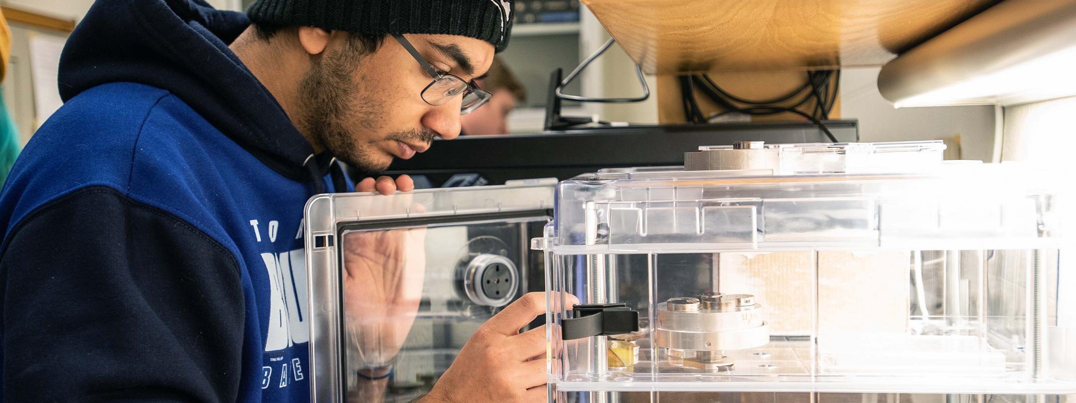 Physics student observing samples in a SEM lab.