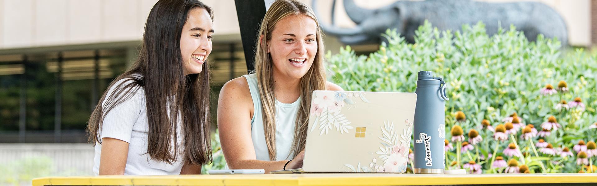 Two students relax on campus in the summer