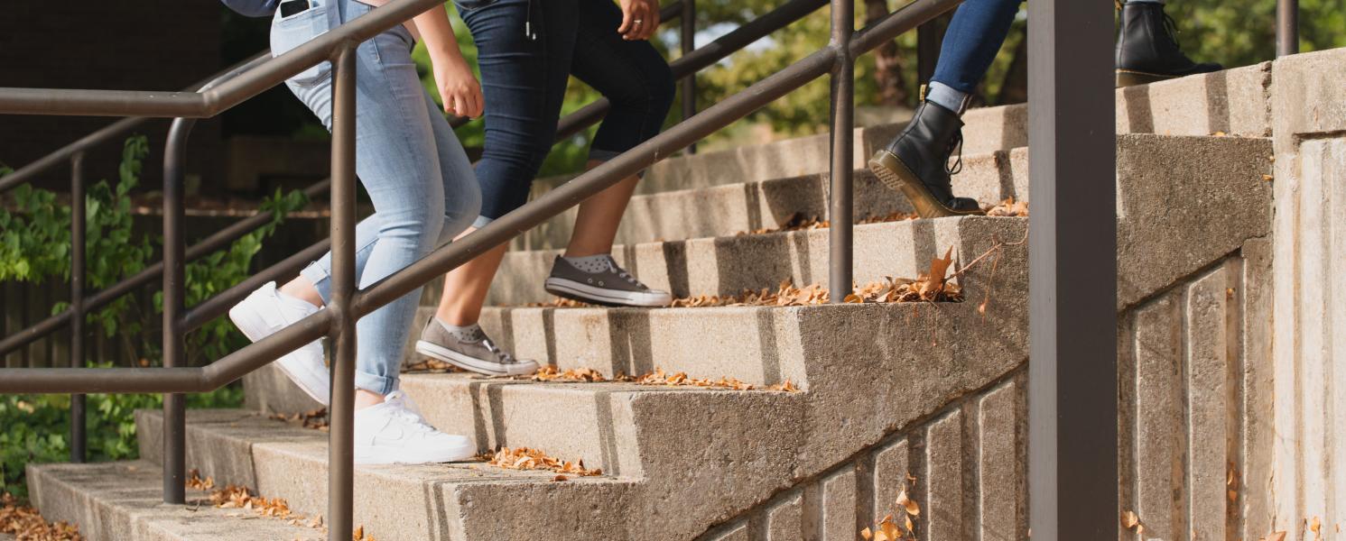 Students walking. Only the legs and feet are showing in the shot.