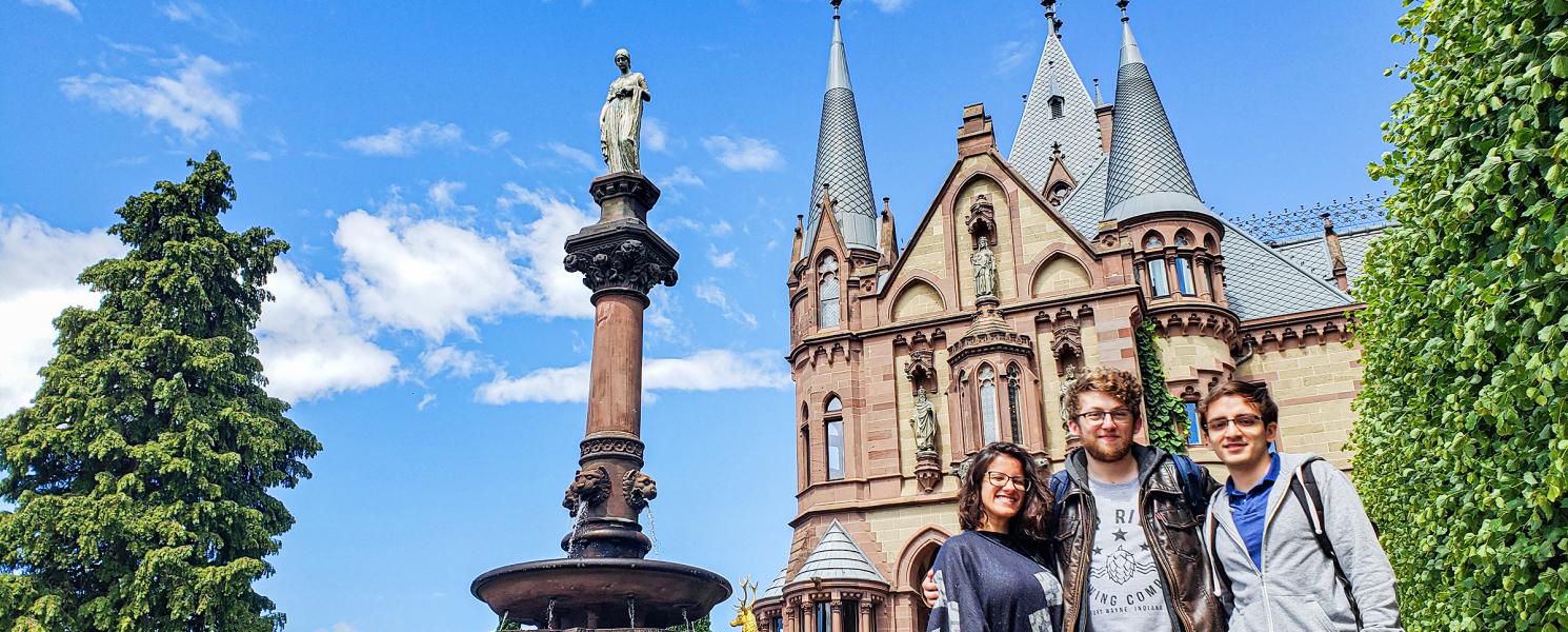 Study abroad students pose in front of old architecture. 