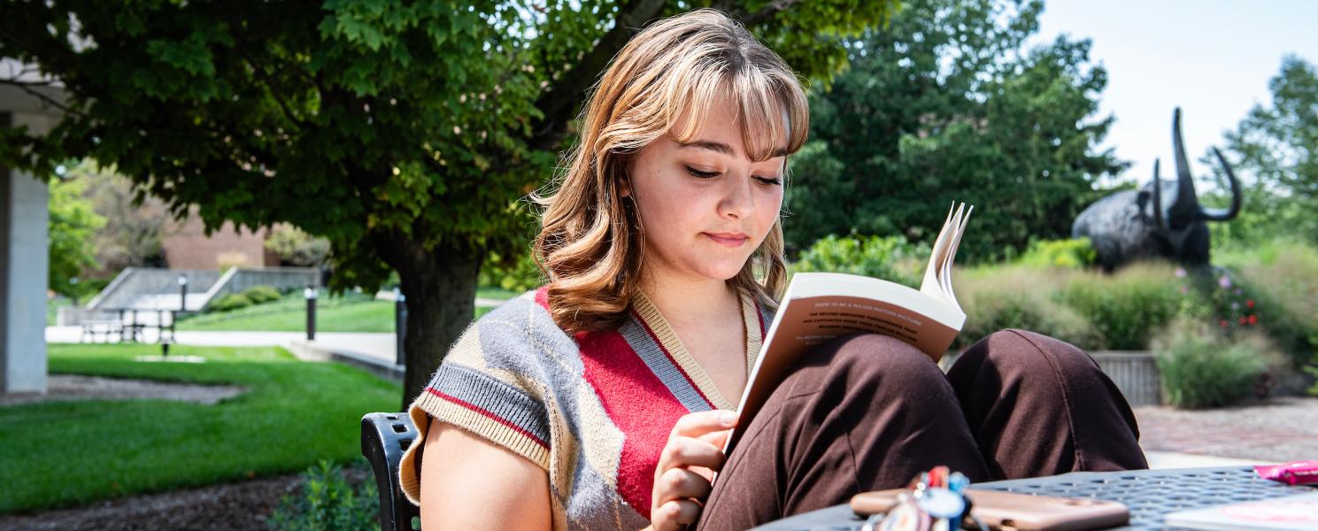 Student reading a book outside.