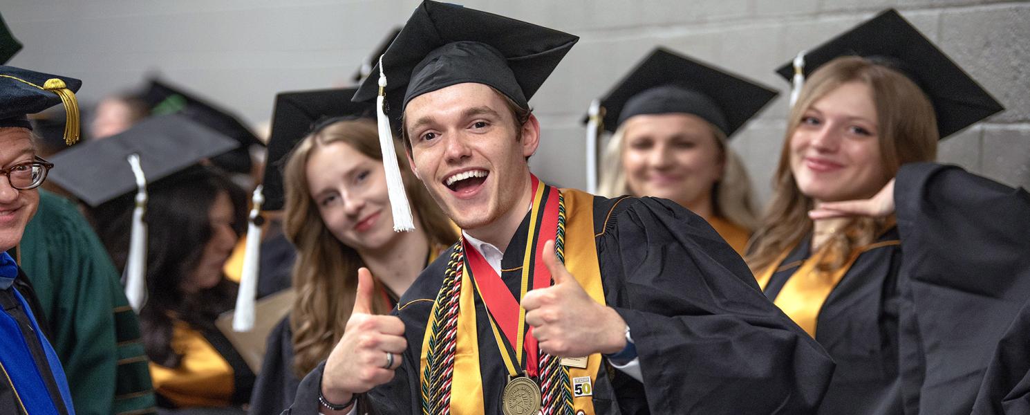 Graduating PFW student giving a thumbs up during commencement