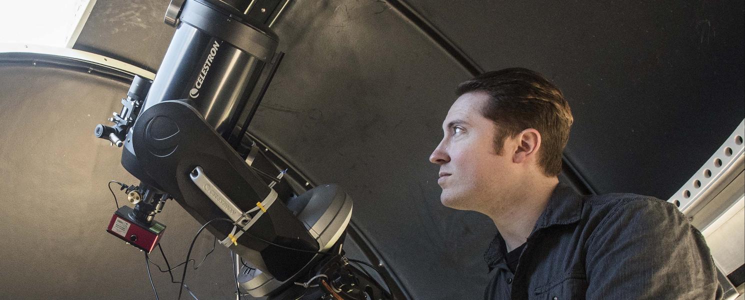 Physics student using a telescope in the observatory lab.