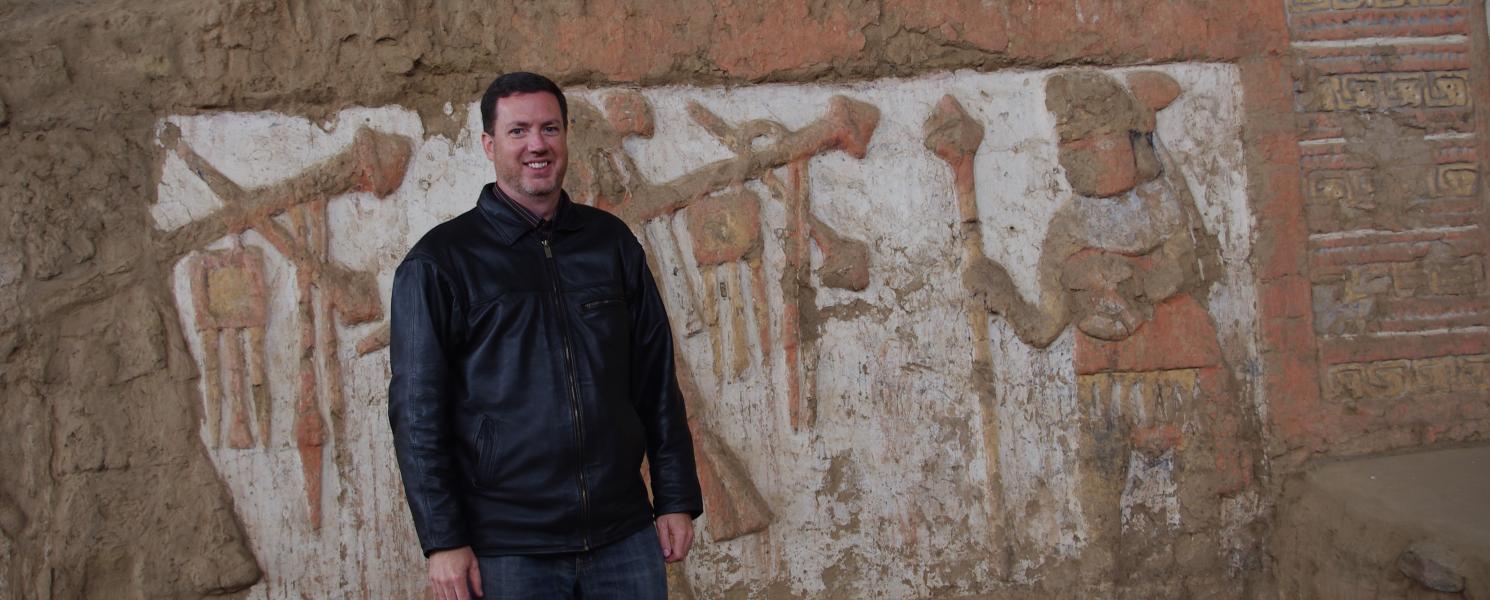 Anthropology professor Richard Sutter in front of Moche frieze in Peru