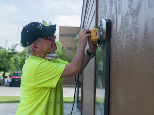 Facilities employee sanding a sign