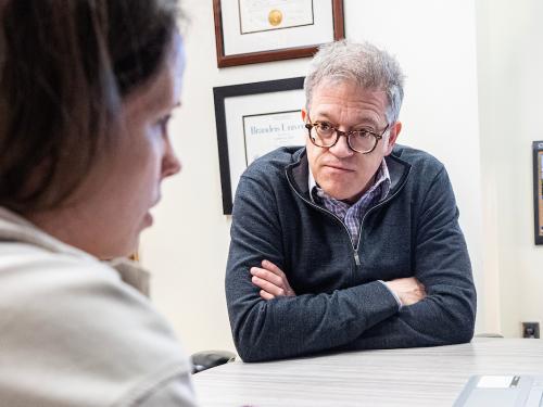 Professor Toole sitting with a student at office hours.